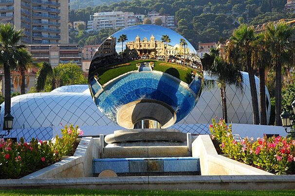 a reflection of the hotel de paris in the fountain
