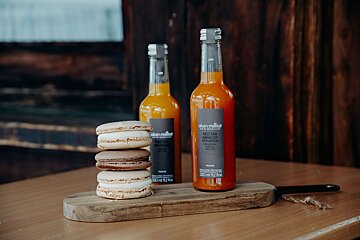 Two bottles of alain millet apricot juice sit on a wooden cutting board
