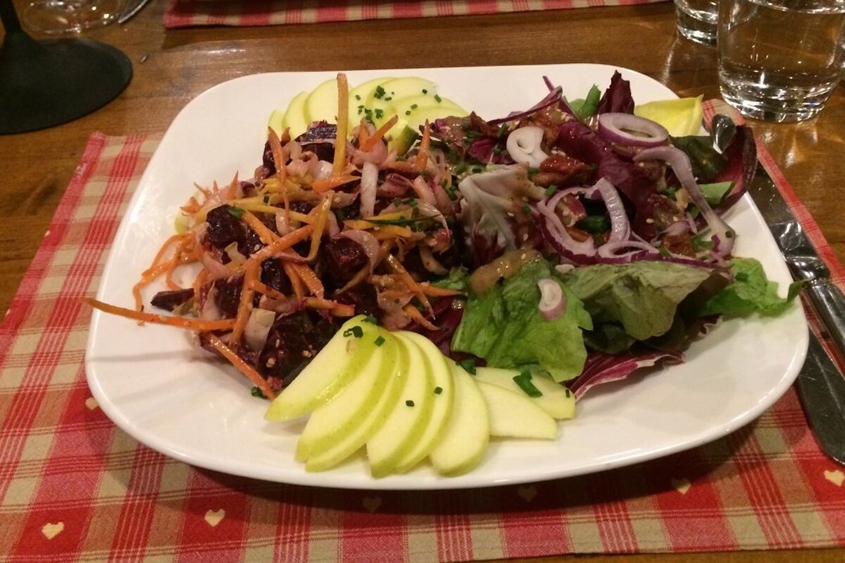 a plate of salad with sliced apple