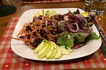a plate of salad with sliced apple