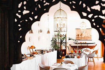 A restaurant with a bird cage hanging from the ceiling