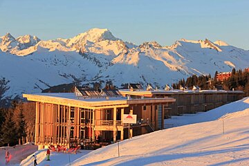 A snowy mountain with a building in the foreground