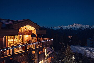 A house with mountains in the background is lit up at night