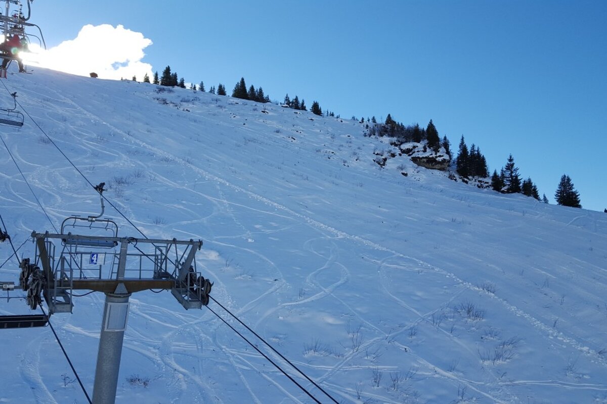 A ski lift is going up a snow covered slope
