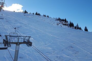 A ski lift is going up a snow covered slope