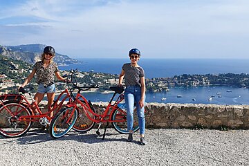 Two women standing next to their bikes with a sign that says ' e-bike ' on it