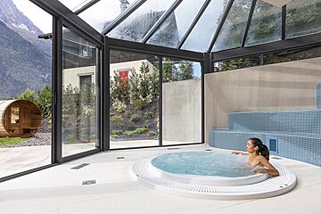 A woman sits in a hot tub with a view of the mountains