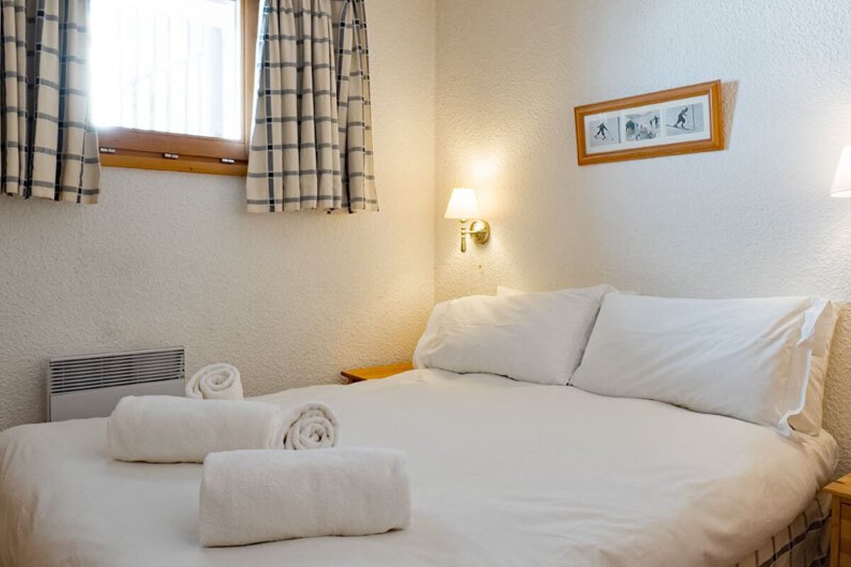 A bedroom with a picture of skiers on the wall above the bed