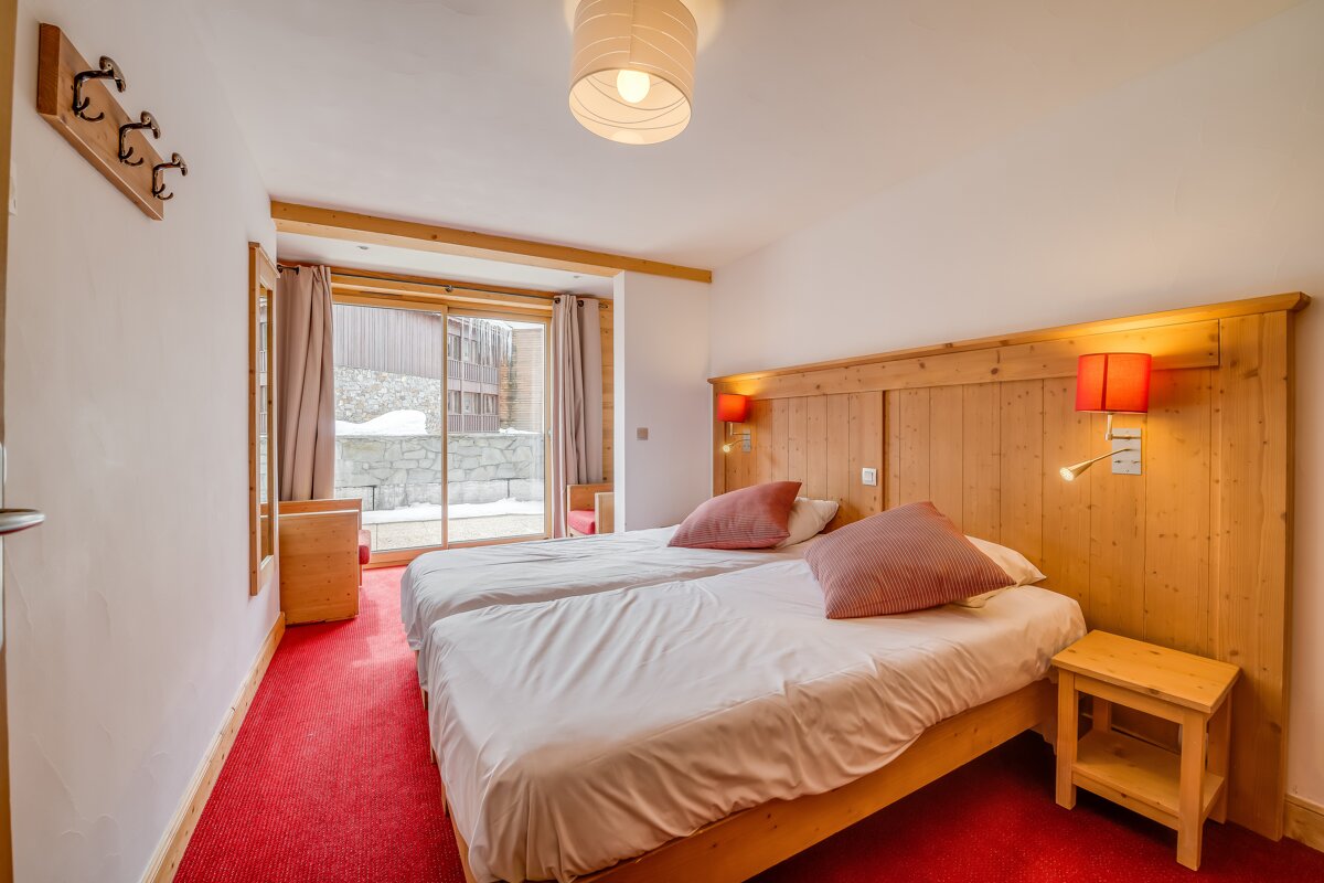 A bedroom with two beds and a nightstand