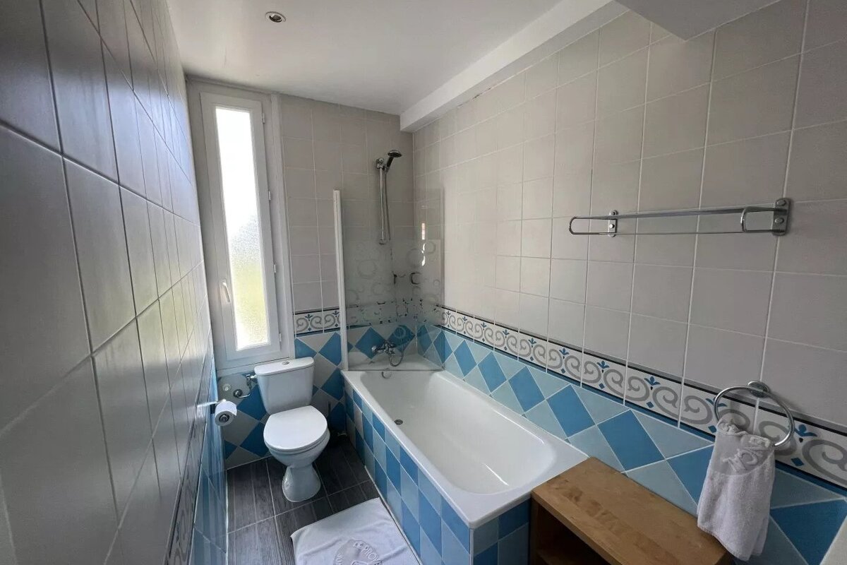 A bathroom with blue and white tiles and a toilet