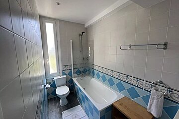 A bathroom with blue and white tiles and a toilet