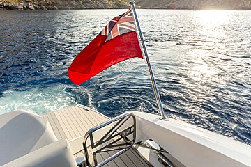 A red british flag is flying from the side of a boat