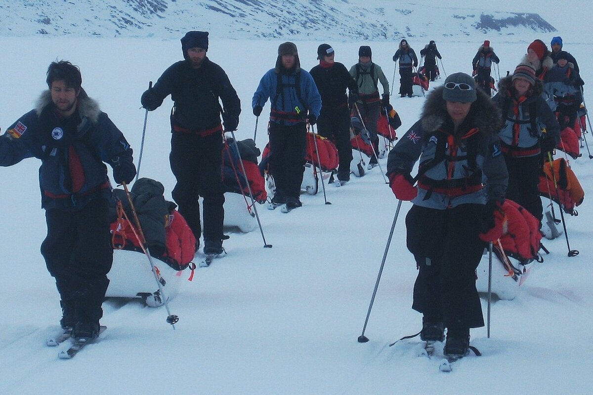 a team of people pulling sleds on snow on skis