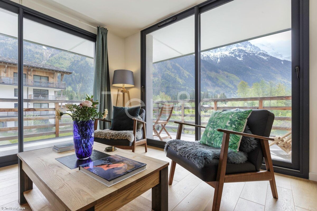A living room with two chairs and a table with a vase of flowers on it
