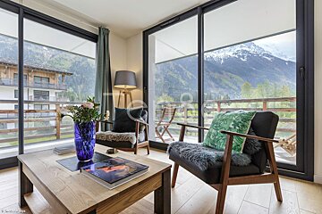 A living room with two chairs and a table with a vase of flowers on it