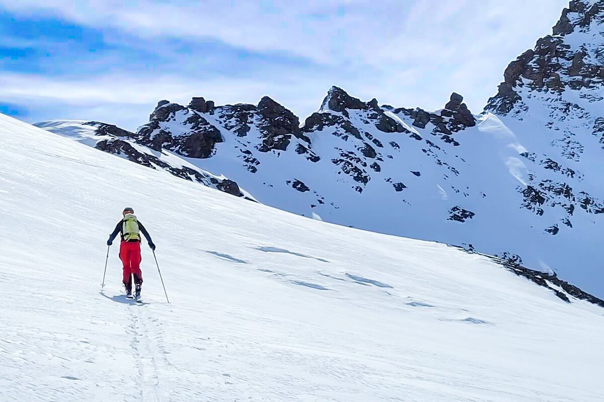 A person skiing down a snowy mountain with rocks in the background