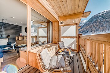 Cozy wooden balcony with breakfast overlooks snowy mountains, connected to a modern room. A perfect winter retreat.