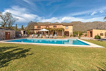 A large swimming pool in front of a house with mountains in the background