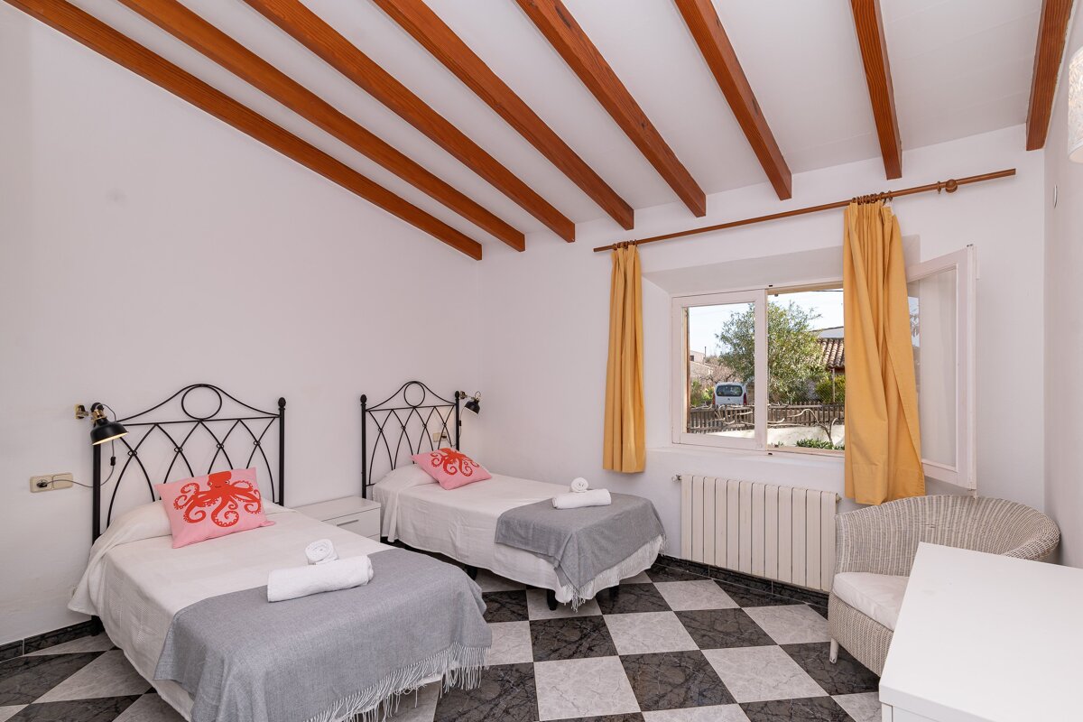 A bedroom with two beds a chair and a window