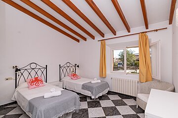 A bedroom with two beds a chair and a window