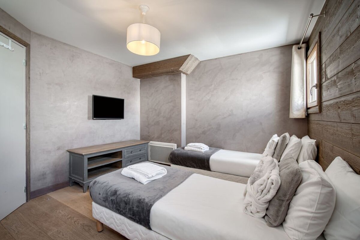 A bedroom with two beds and a flat screen tv