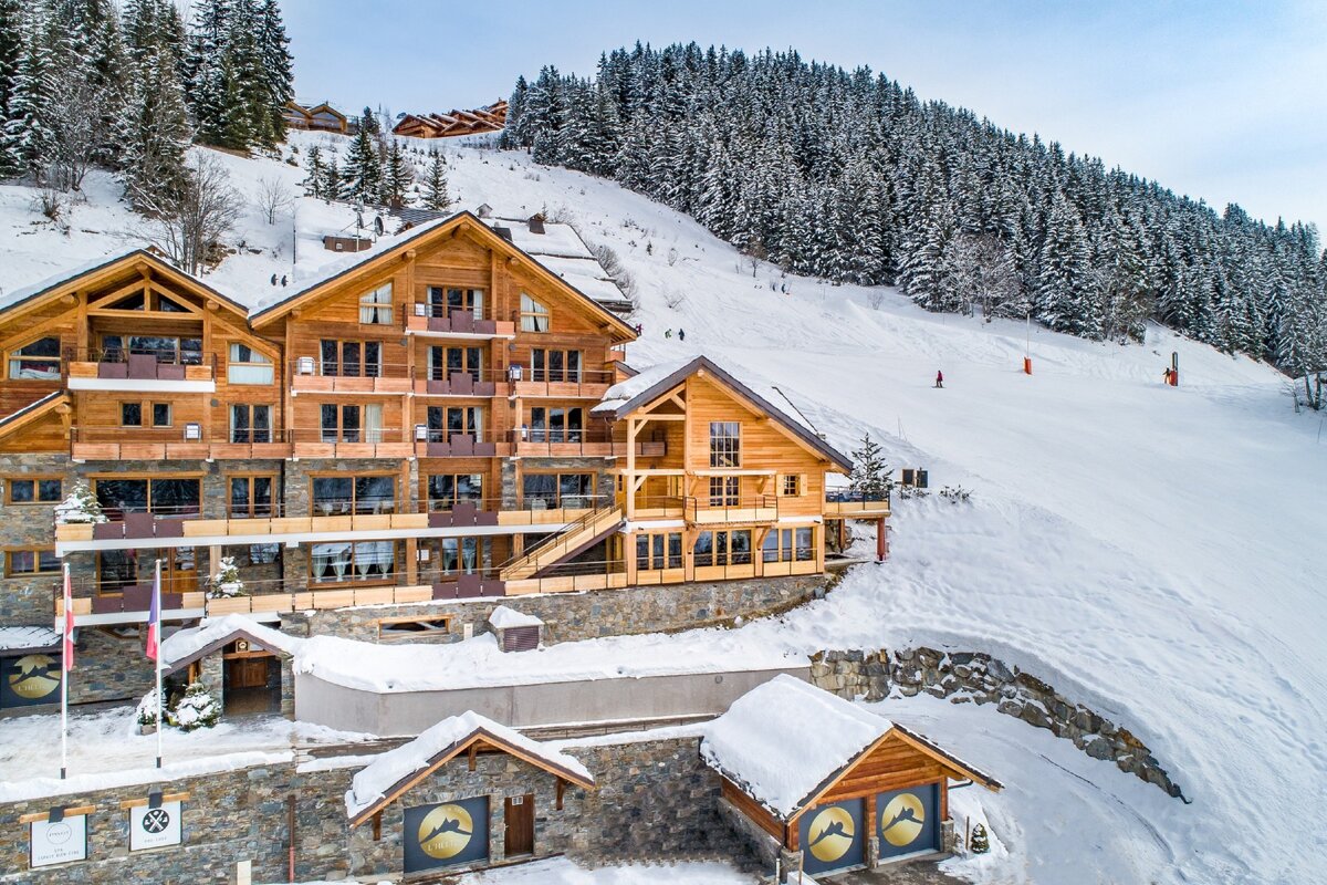 A large wooden building is surrounded by snow covered trees