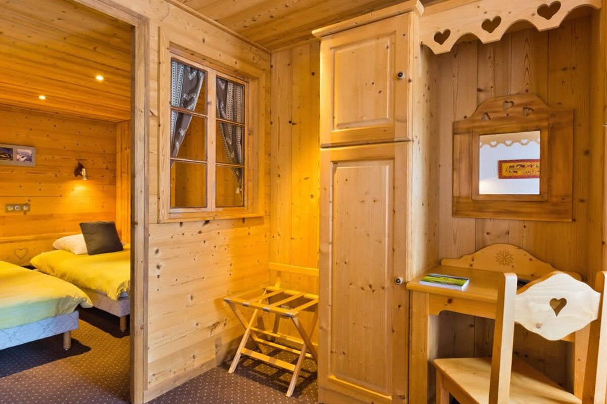 A wooden room with two beds and a desk with a book on it