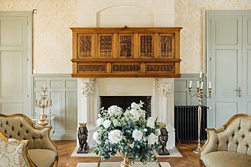 A vase of white flowers sits in front of a fireplace