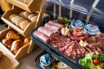 A variety of meats and cheeses are displayed on a buffet table