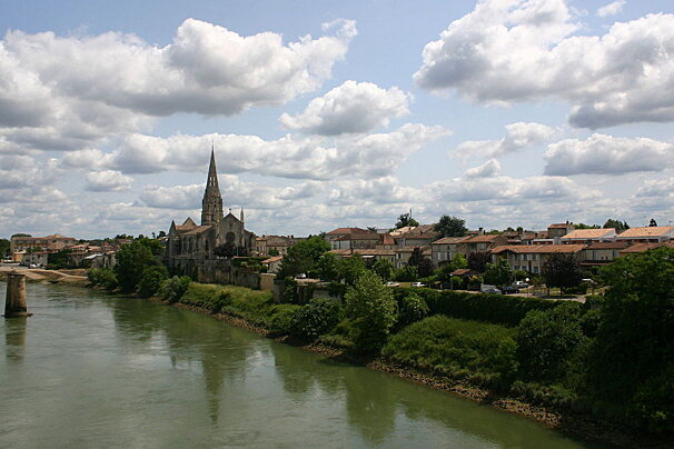 A town seen across a river, a church in the distance