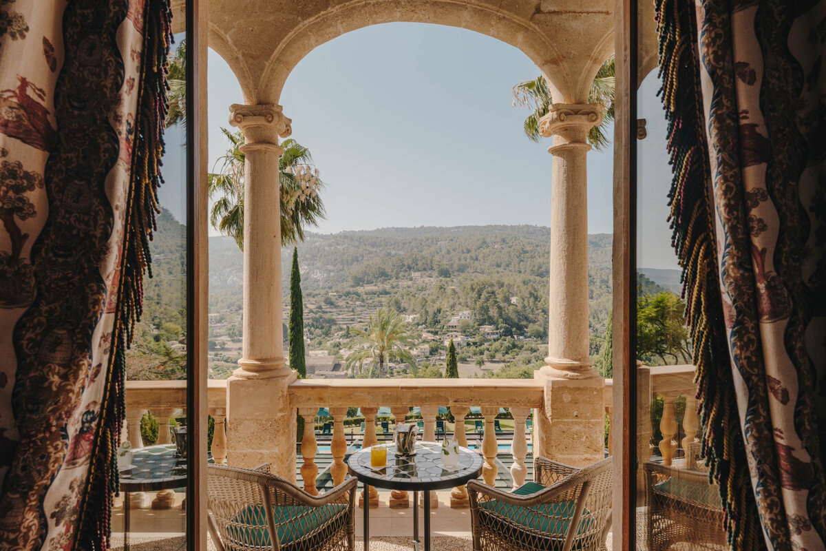 A balcony with two chairs and a table with a drink on it