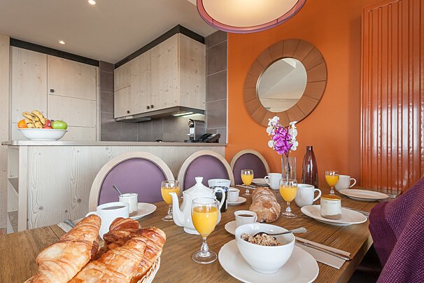 A dining room table with a basket of croissants on it