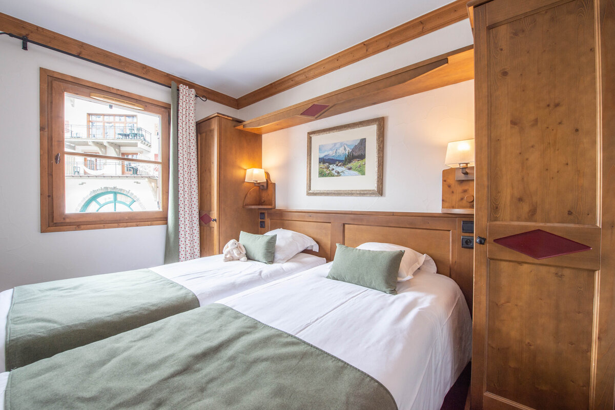 A bedroom with two beds and a painting on the wall