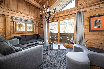 A living room in a log cabin with a chandelier hanging from the ceiling