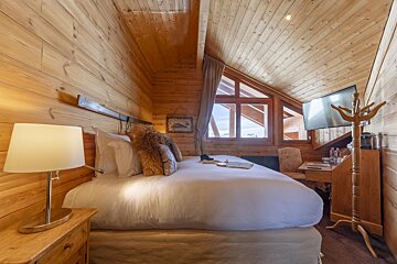 A bedroom with a large bed and a television