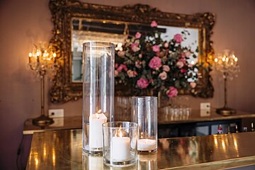 Three candles are in clear cylinders on a table