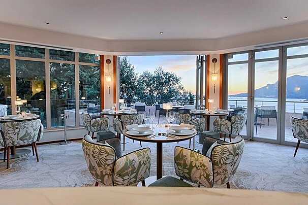 A dining room with tables and chairs and a view of the ocean