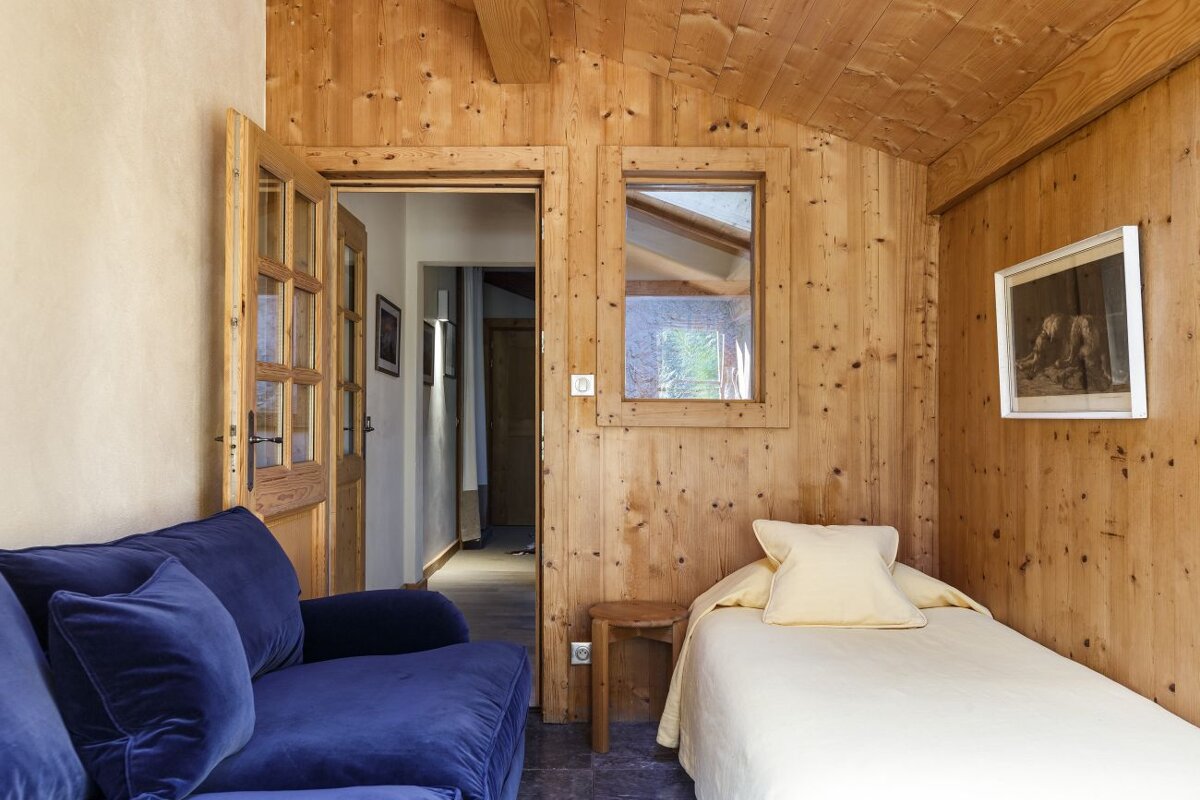 A bedroom with a blue couch and a single bed