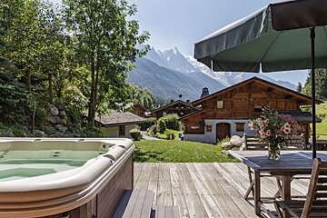 A hot tub sits on a deck with mountains in the background