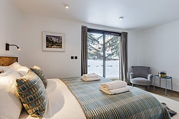 A bedroom with a king size bed and a chair