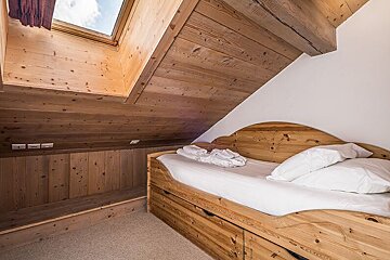 A wooden bed in a room with a skylight above it