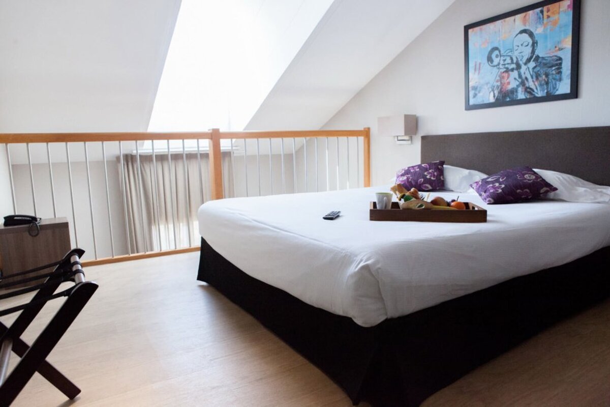 A hotel room with a tray of food on the bed