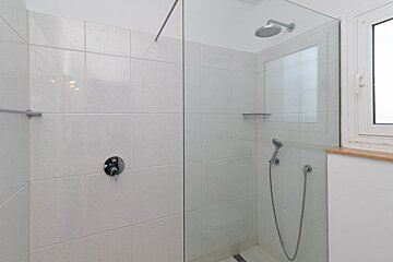 A shower with a glass door and a window