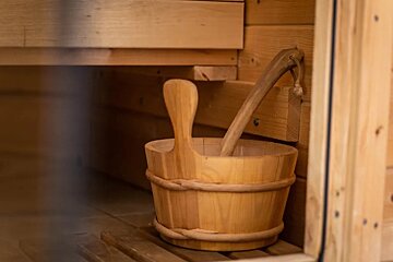 A wooden bucket with a wooden spoon inside of a wooden sauna