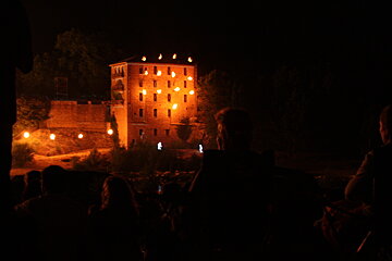 a stone building lit up with torches and projections