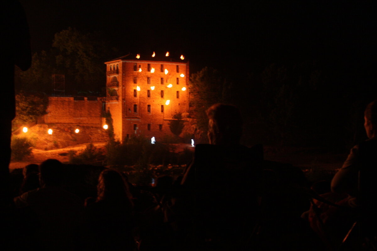 a stone building lit up with torches and projections