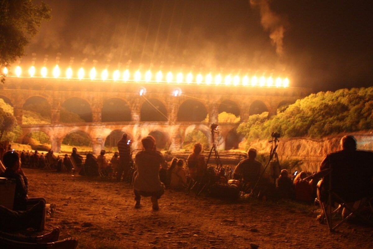 A group of people watching a bridge with flames coming out of it