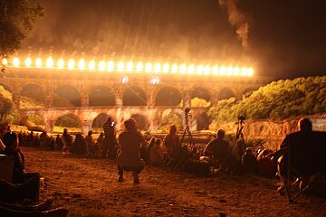 A group of people watching a bridge with flames coming out of it