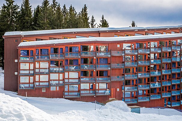 A red building with blue balconies is covered in snow