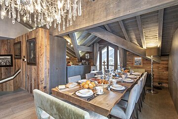 A dining room with a long table and chairs and a chandelier